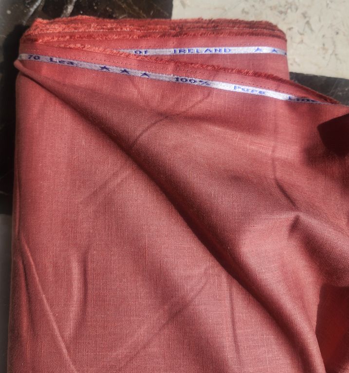 Red fabric with a measuring tape on top, on a textured surface