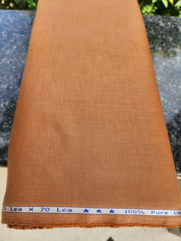 Brown fabric with a measuring tape at the bottom, on a blurred natural background